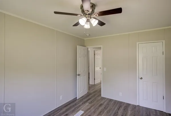an empty room with wooden floor and ceiling fan