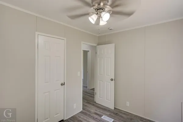 a view of empty room with wooden floor and fan