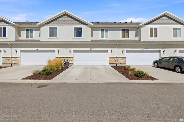 28 East Ginger Gold Road Santaquin, UT 84655 - Photo 4 of 36 Townhome exterior featuring stucco siding, stone accents, and multiple attached garages with concrete driveways