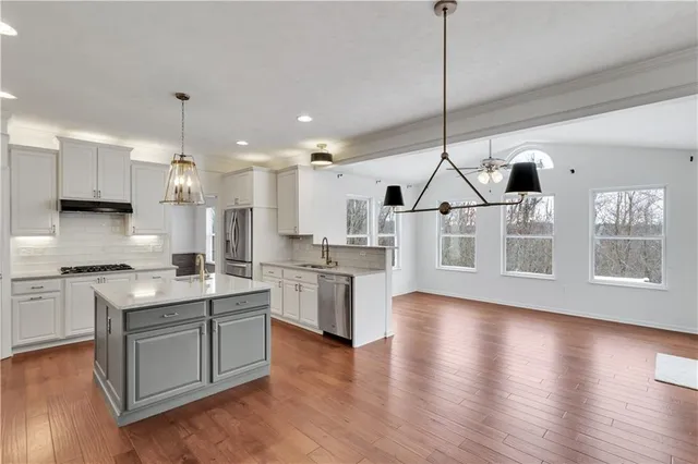a view of empty room with wooden floor and kitchen view