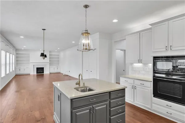 a kitchen with kitchen island granite countertop a sink a stove and wooden floor