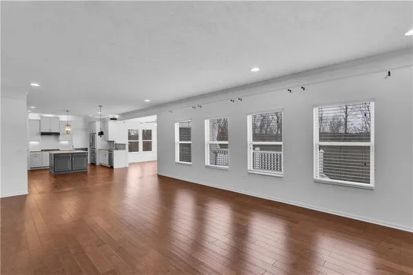 a view of empty room with wooden floor and kitchen view