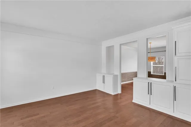 a view of an empty room with wooden floor and windows