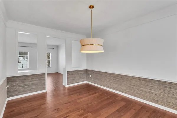a view of an empty room with wooden floor and windows