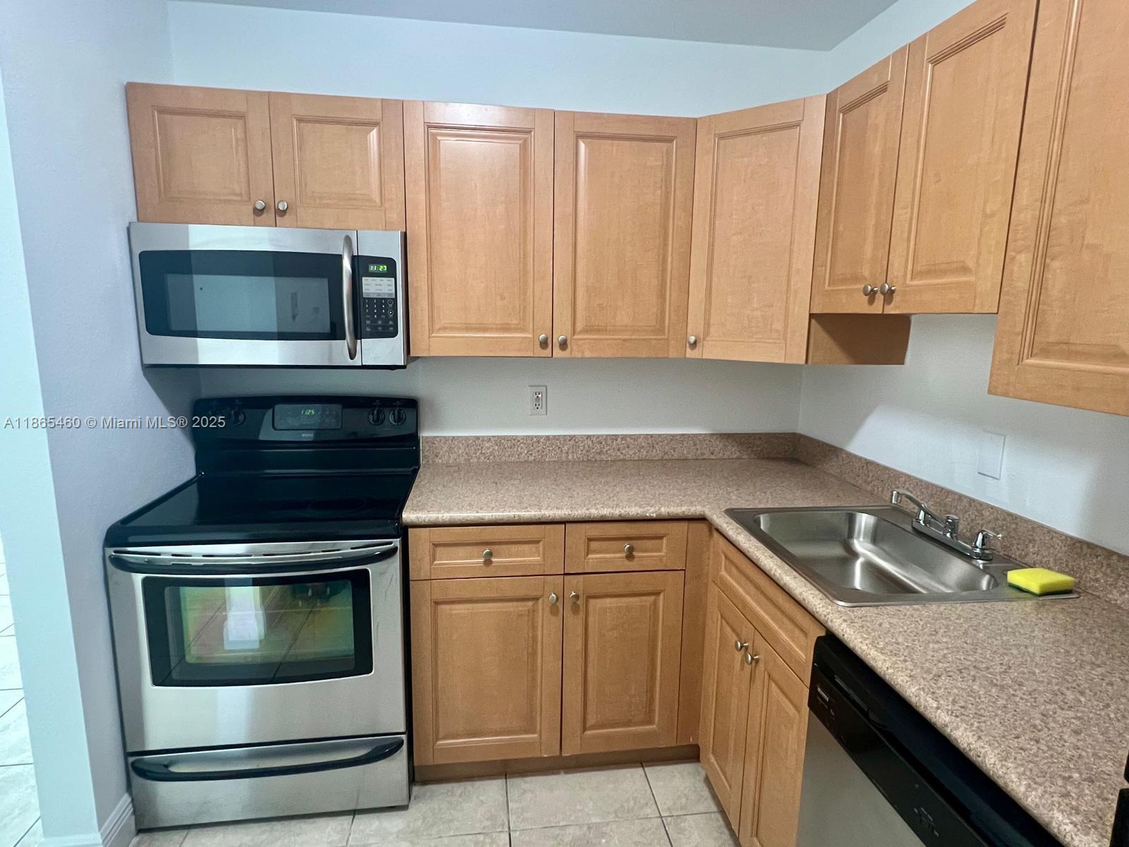 4810 Northwest 79th Avenue, Unit 305 Doral, FL 33166 - Photo 12 of 28 a kitchen with granite countertop a stove sink and cabinets