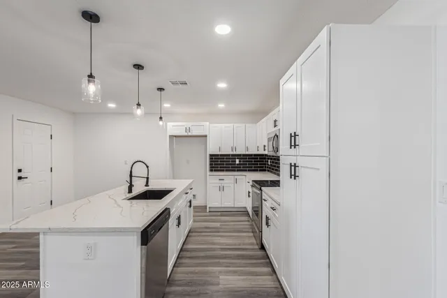 a kitchen with kitchen island a sink a counter top space stainless steel appliances and cabinets
