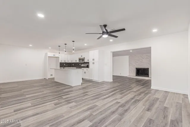 an empty room with wooden floor and kitchen view