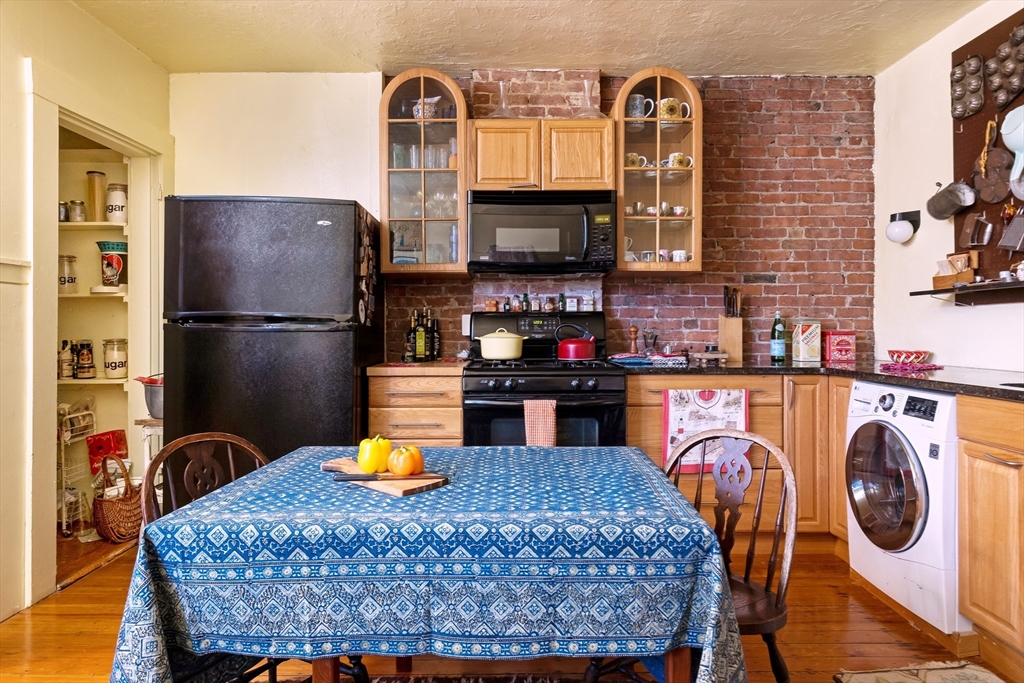 a kitchen with a refrigerator a stove and a dining table with wooden floor