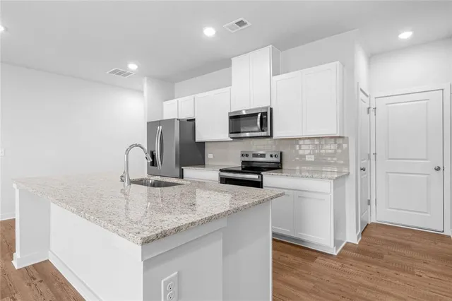 a kitchen with kitchen island granite countertop a sink appliances cabinets and counter space