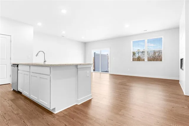 a kitchen with stainless steel appliances granite countertop a dishwasher a stove a refrigerator with white cabinets and wooden floor