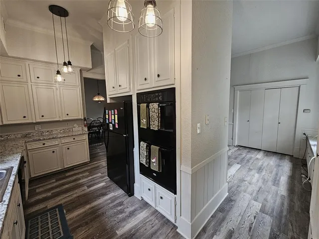 a kitchen with granite countertop white cabinets and refrigerator