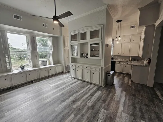 a kitchen with stainless steel appliances a stove top oven a refrigerator a dining table and chairs with wooden floor