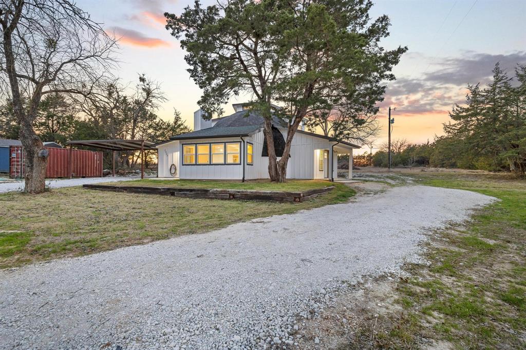 a view of a house with a yard and large trees