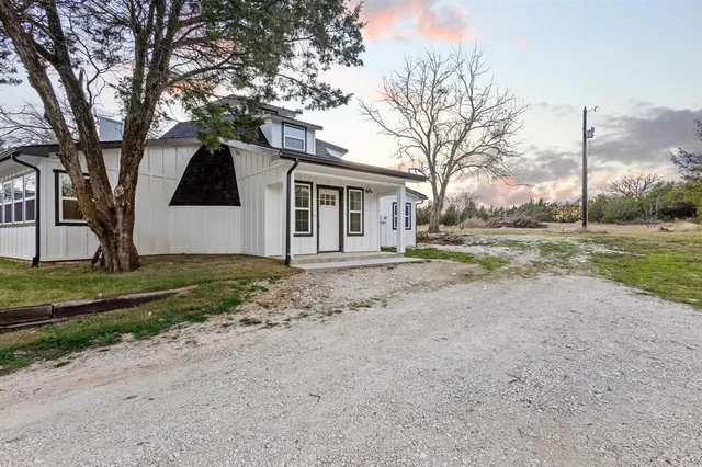 a view of a house with a yard and large trees