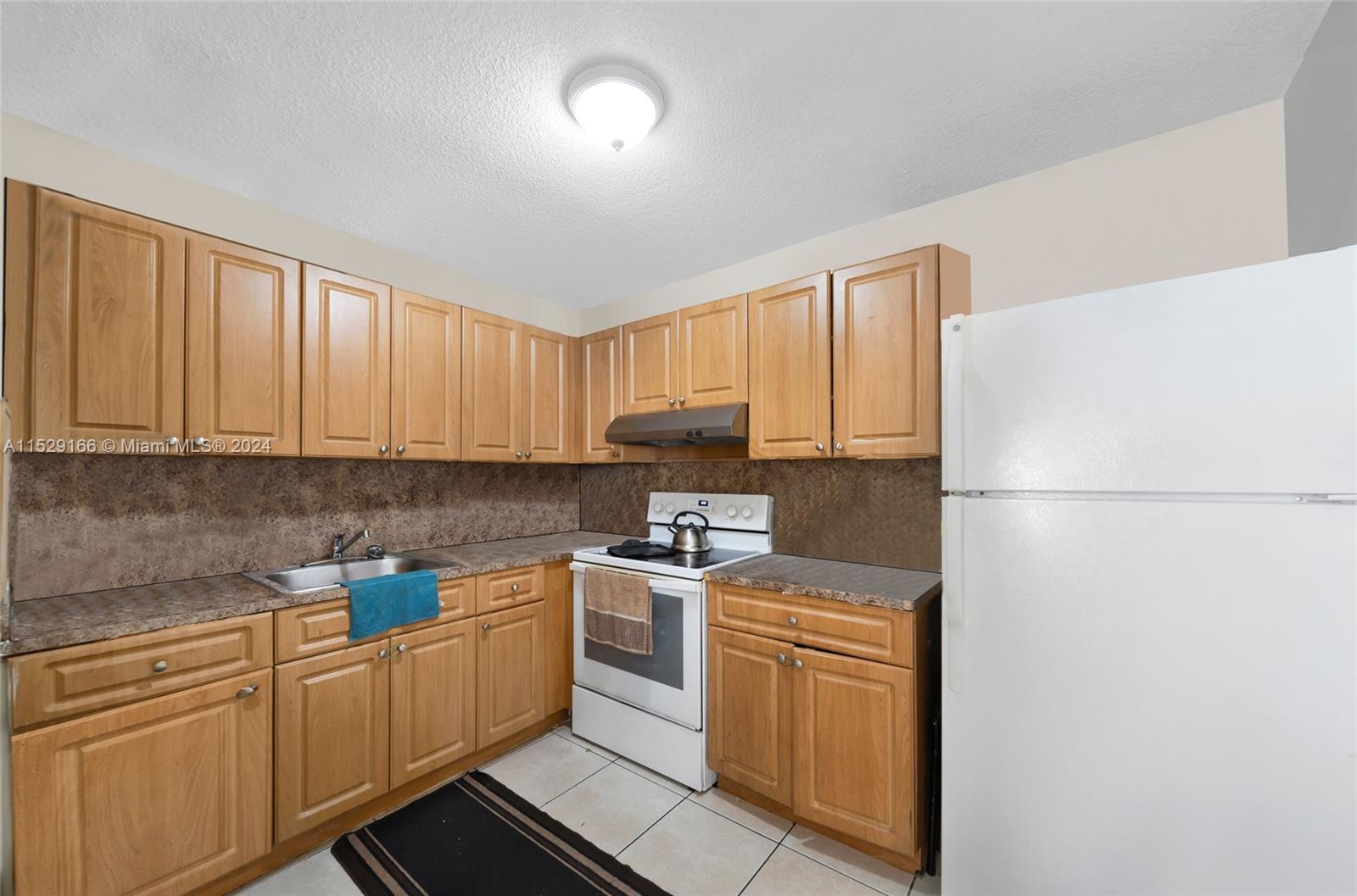 13240 Port Said Road Opa-Locka, FL 33054 - Photo 17 of 21 a kitchen with stainless steel appliances granite countertop a refrigerator sink stove and white cabinets