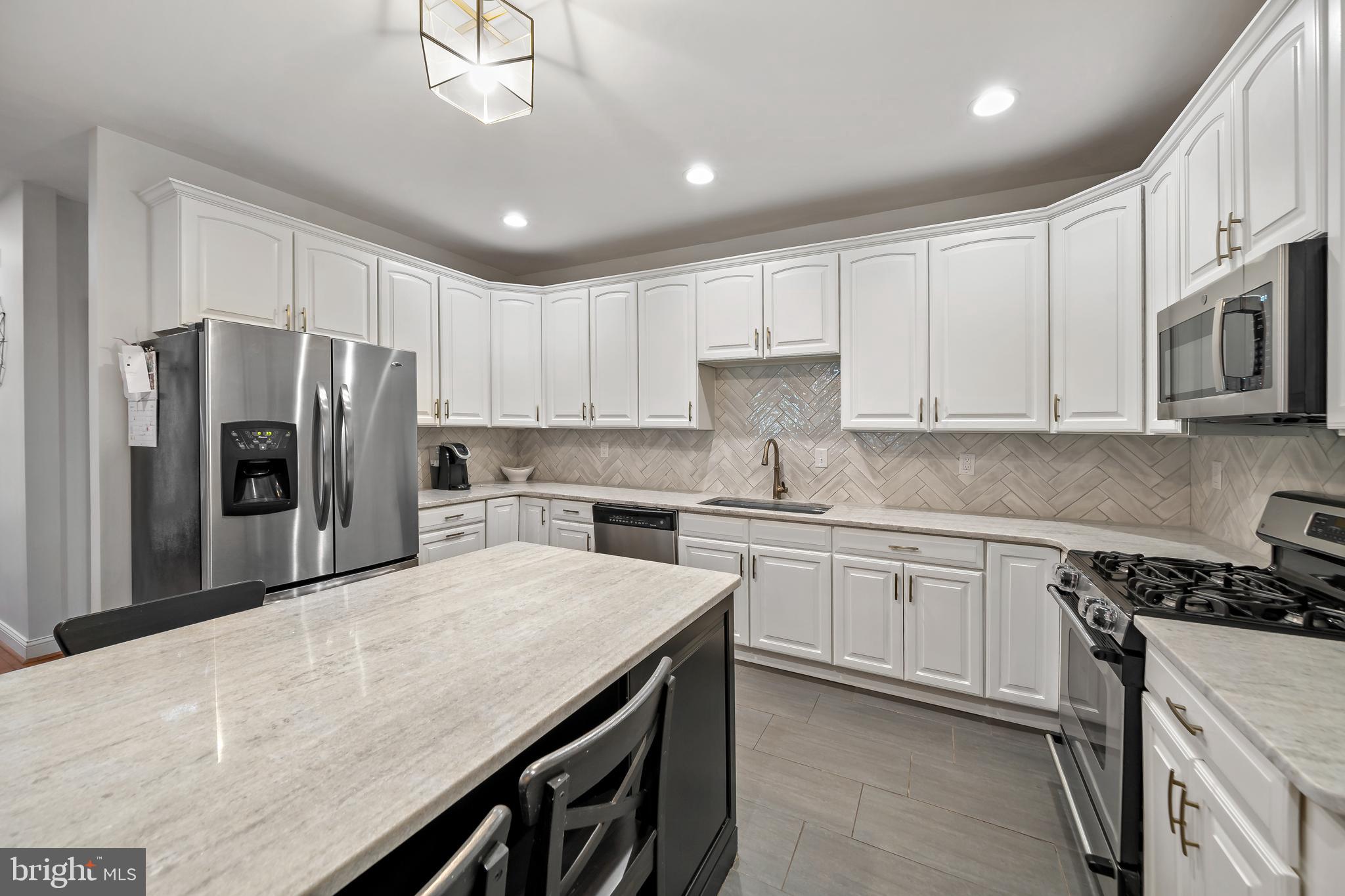 a kitchen with stainless steel appliances granite countertop a refrigerator a sink dishwasher a stove and white cabinets