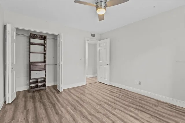 an empty room with wooden floor closet and windows