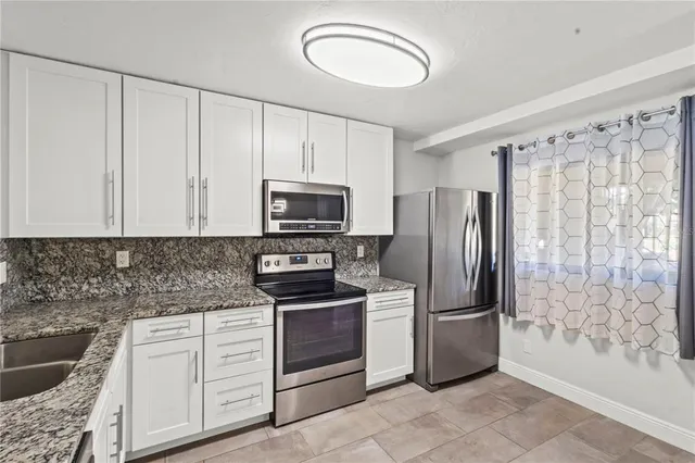 a kitchen with granite countertop a refrigerator stove and sink