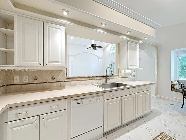 a large white kitchen with a sink and dishwasher a refrigerator with white cabinets