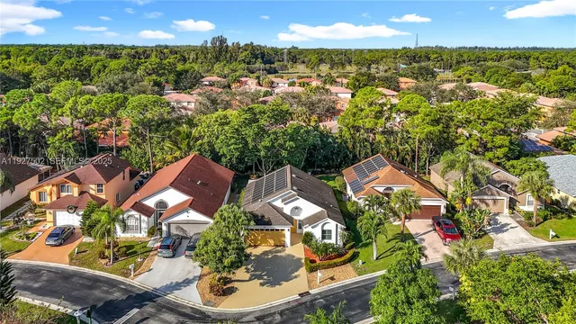 an aerial view of a residential apartment building with a yard and large trees