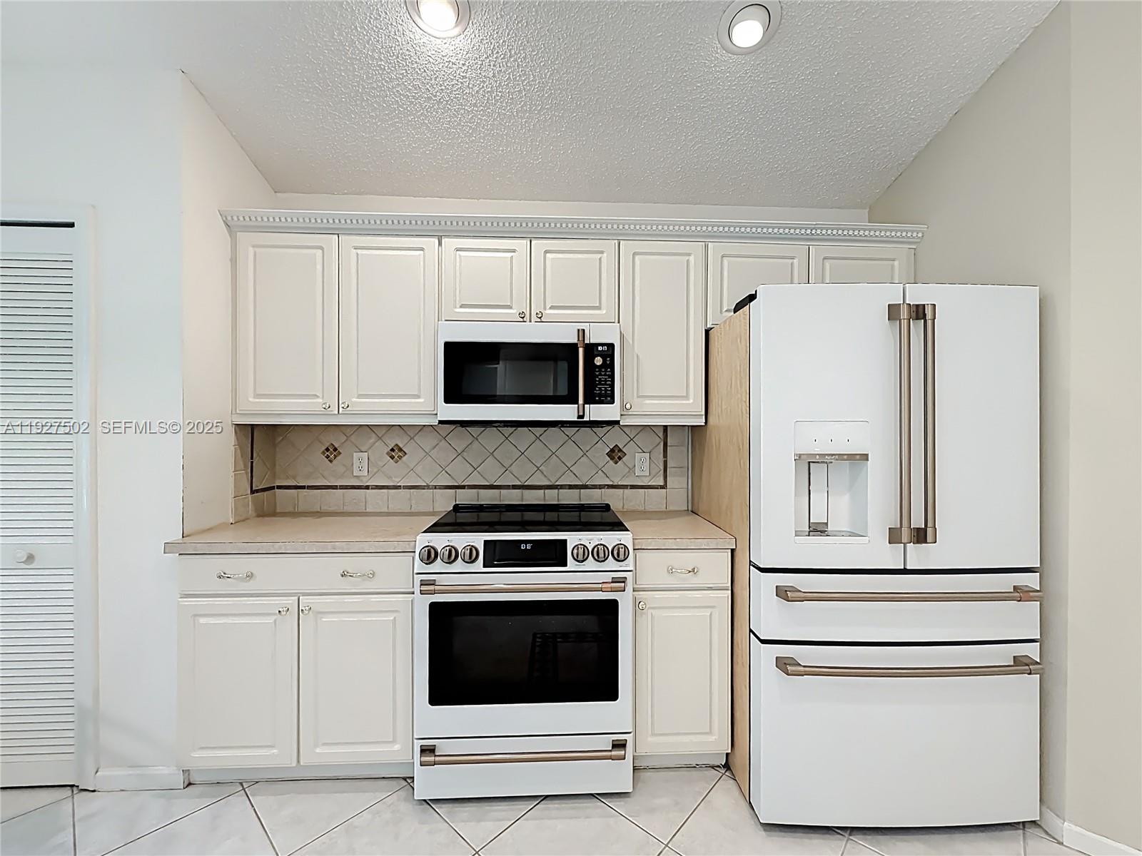 356 Hammocks Trail Greenacres, FL 33413 - Photo 9 of 41 a kitchen with white cabinets and white appliances