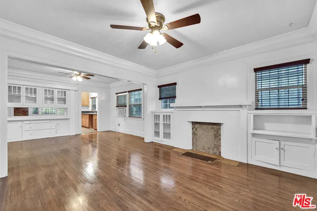 a view of an empty room with window and wooden floor