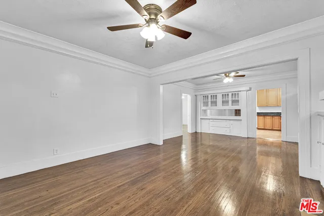 a view of an empty room with a window and wooden floor