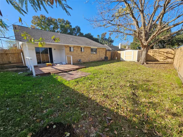 a backyard of a house with table and chairs plants and large tree