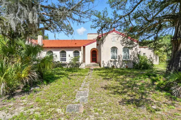 a white house sitting in middle of a yard