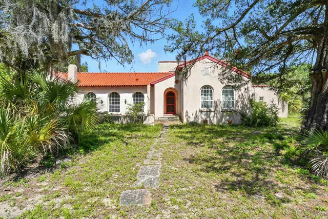 a white house sitting in middle of a yard
