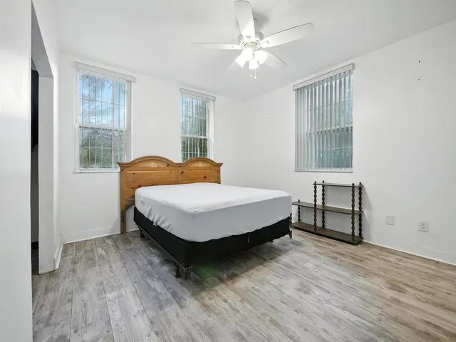 a bedroom with a bed table and two window