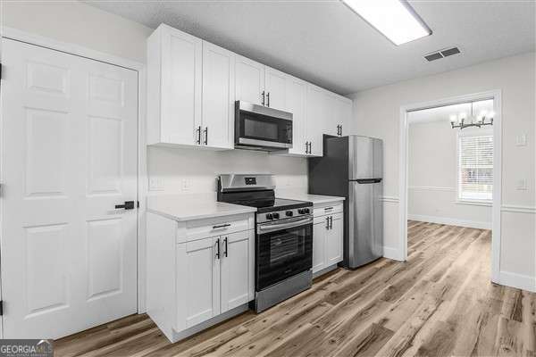 804 Ridgewood Way Hinesville, GA 31313 - Photo 10 of 27 a kitchen with stainless steel appliances white cabinets and wooden floors
