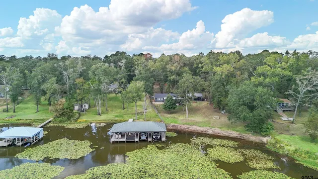 an aerial view of a house lake and trees in the background