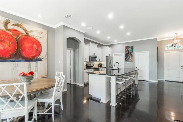 a kitchen with stainless steel appliances kitchen island granite countertop a dining table chairs and granite counter tops