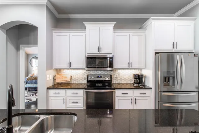 a kitchen with stainless steel appliances granite countertop a refrigerator stove and sink