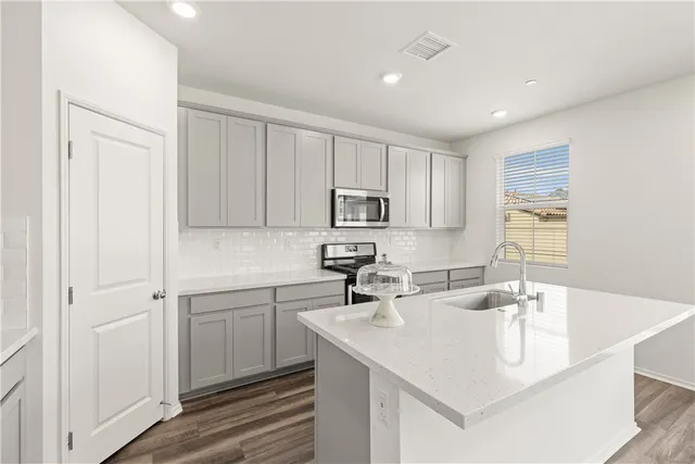 a kitchen with kitchen island a sink appliances and cabinets