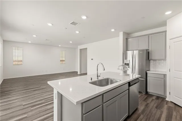 a kitchen with kitchen island a counter top space a sink stainless steel appliances and cabinets