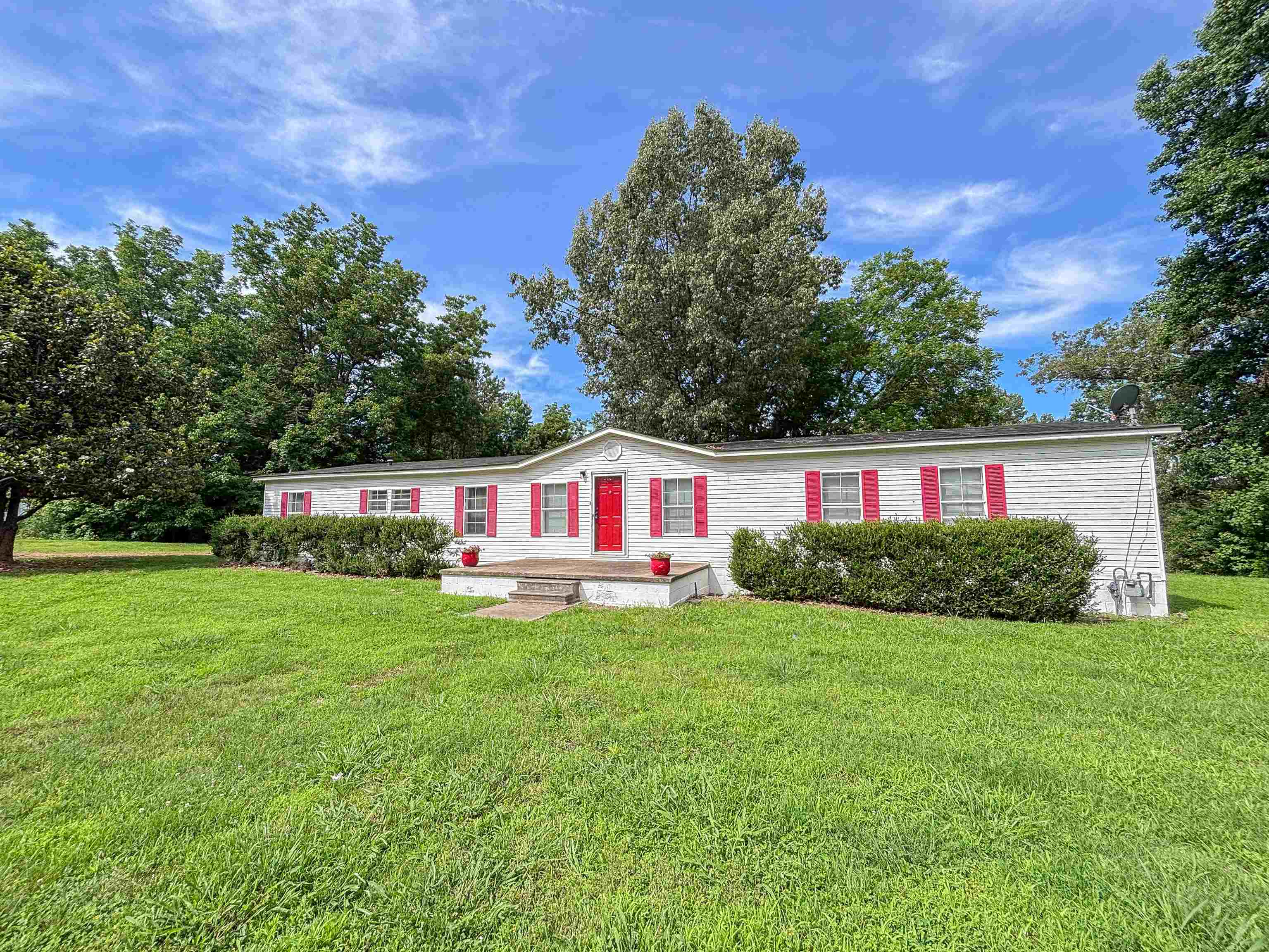 2847 Holly Grove Road Covington, TN 38019 - Photo 4 of 36 White siding exterior with a vibrant red front door and matching window shutters