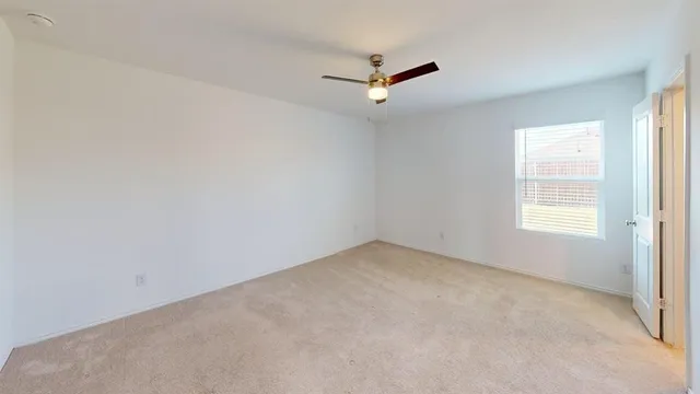 an empty room with a window and a fan