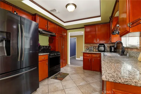 a kitchen with stainless steel appliances granite countertop a refrigerator a stove and a sink