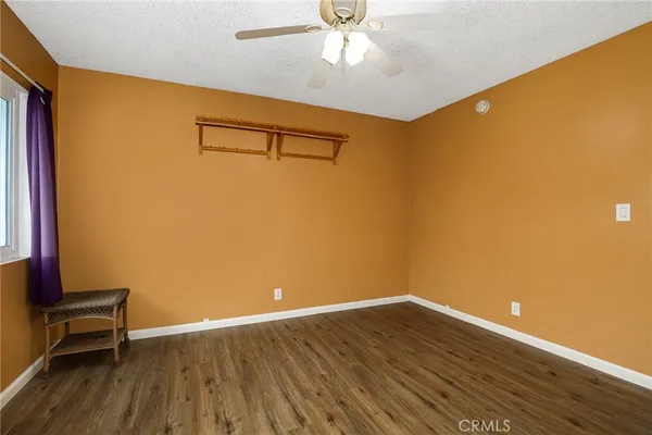 a view of a room with wooden floor and a ceiling fan