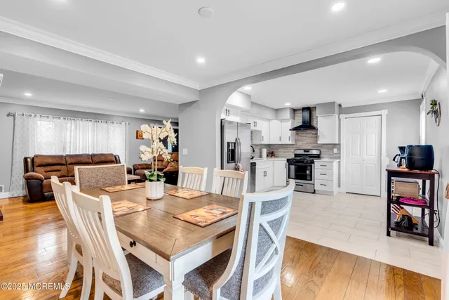 a kitchen with stainless steel appliances kitchen island granite countertop a dining table chairs refrigerator and a stove