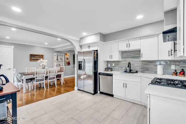 a kitchen with stainless steel appliances kitchen island granite countertop a table chairs microwave and sink