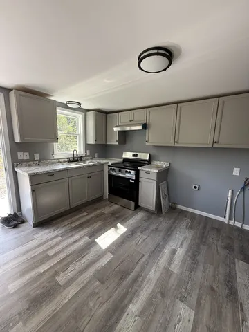 a kitchen with stainless steel appliances granite countertop a sink a stove and a refrigerator