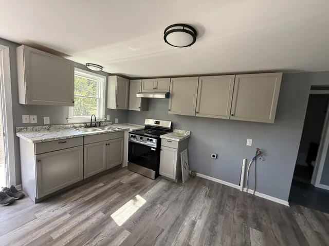 a kitchen with granite countertop a sink cabinets and stainless steel appliances