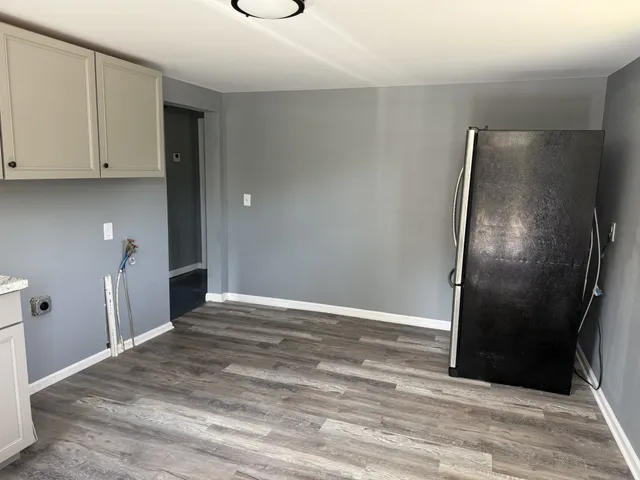 a view of an empty room with wooden floor and a mirror