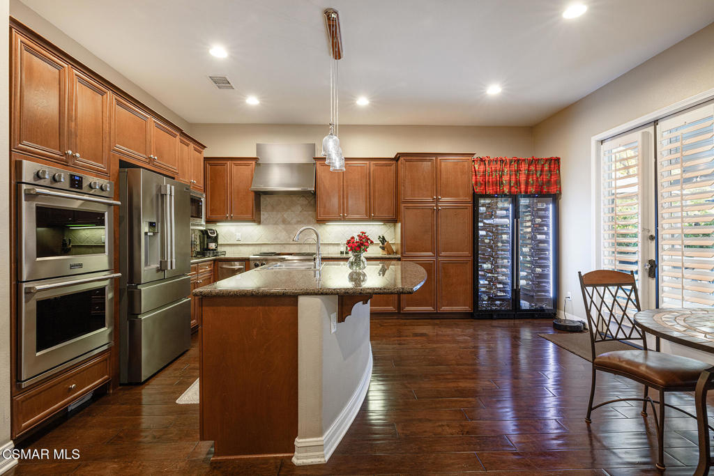 5019 Corral Street Simi Valley, CA 93063 - Photo 9 of 50 a kitchen with stainless steel appliances granite countertop a refrigerator a stove top oven a sink dishwasher and white cabinets with wooden floor