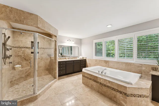 a bathroom with a tub a sink a mirror and a shower