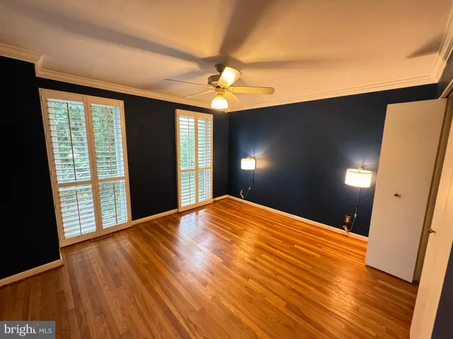 a view of empty room with wooden floor and fan