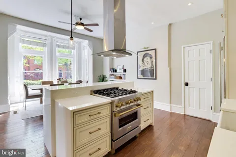 a kitchen with a stove a sink and a wooden floor